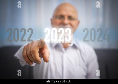 Fingerdruck der blauen Start 2023-Taste auf der virtuellen Benutzeroberfläche auf grauem Hintergrund mit Platz für Text. Konzept des neuen Jahres. Businessman Pressing Stockfoto