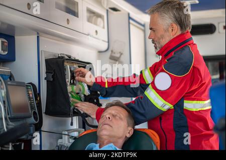 Ambulanzarzt bereitet den Patienten auf Oxygenierung vor Stockfoto