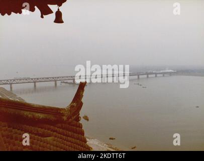 Ein Dampfzug überquert eine Brücke über den Qiantang-Fluss in Hangzhou, China, auf einem Foto, das von der Spitze der sechs-Harmonien-Pagode im Dezember 1981 aufgenommen wurde Stockfoto