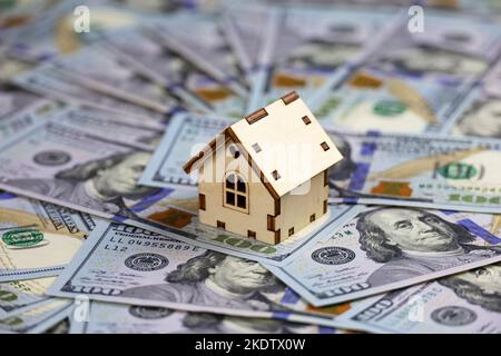 Holzhausmodell auf dem Hintergrund von US-Dollar-Banknoten. Wohnungsmarkt, Kauf oder Vermietung von Immobilien Stockfoto