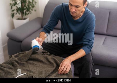 Der Mann entfernt Stofftabletten mit Flusensieb. Stockfoto