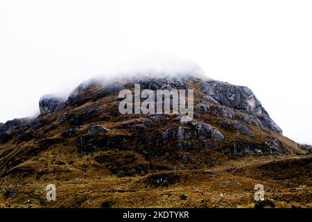 Ein dramatischer Blick auf einen nebligen hohen Gipfel im Nationalpark von der Region im Anden-Hochland Ecuadors an einem regnerischen und bewölkten Tag Stockfoto