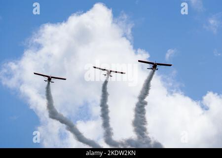 Liepaja, Lettland - 7. August 2022: Drei rote Sportflugzeuge mit Rauchstreifen machen während der Baltic International Airshow einen Aerobatic-Gruppenflug Stockfoto