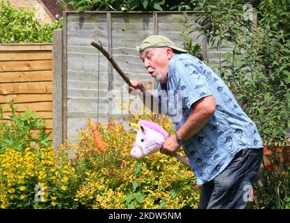 Älterer oder älterer Mann, der spielt. So tun, als würde man auf einem Pferd reiten und lachen. Spaß haben. Stockfoto