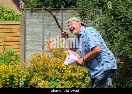 Älterer oder älterer Mann, der spielt. So tun, als würde man auf einem Pferd reiten und lachen. Spaß haben. Stockfoto