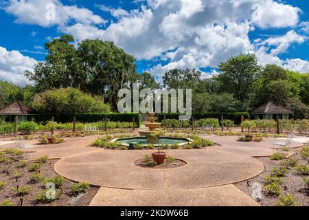 Eine Gasse im Garten mit wunderschönen ausgefallenen Pflanzen und einem Brunnen im Cypress Grove Park, Orlando, Florida. Stockfoto