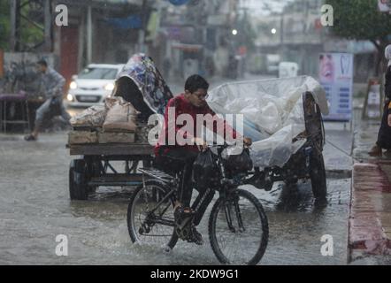 Ein palästinensisches Kind sah im Flüchtlingslager Jabalia inmitten des starken Regens im nördlichen Gazastreifen ein Fahrrad auf der Straße fahren. Stockfoto