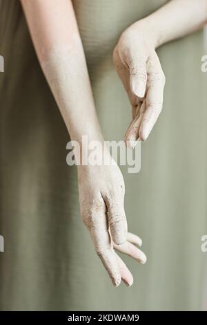 Nahaufnahme eleganter weiblicher Hände, die mit weißer Farbe vor minimalem Hintergrund bedeckt sind Stockfoto