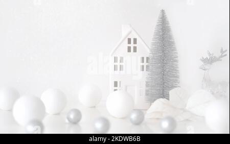 Weihnachtskomposition. Weihnachtskugeln weiß und silber, dekoratives Haus, weihnachtsbaum auf weißem Hintergrund Stockfoto