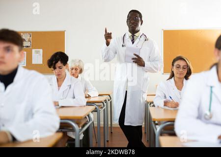 Professor im Gespräch mit Medizinstudenten im Klassenzimmer Stockfoto