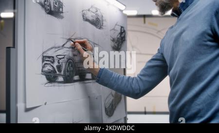 Zwei verschiedene männliche Automobildesigner diskutieren und entwickeln futuristisches Elektroauto-Design. Eine Zeichnung Skizzen auf Whiteboards, andere halten Tablet-Computer. Auto-Design-Entwicklungsstudio. Stockfoto