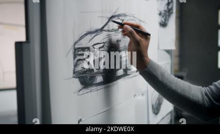 afroamerikanischer Designer aus dem Automobilbereich zeichnet Skizzenvorlage mit Marker auf dem Whiteboard und entwickelt futuristisches Design für Elektroautos. Er arbeitet in der Auto-Design-Entwicklung modernes Studio. Stockfoto