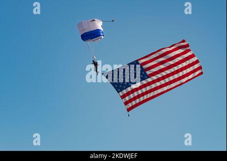 Ein Kadett der United States Air Force Academy vom Wings of Blue Demonstrationsteam zeigt die amerikanische Flagge während der Eröffnungszeremonie der Aviation Nation 2022 auf der Nellis Air Force Base, Nevada, am 4. November 2022. Die primäre Mission der Wings of Blue ist es, den Basic Freefall Parachuting Course der US Air Force Academy, bekannt als Airmanship 490, zu leiten. (USA Luftwaffe Foto von Airman 1. Klasse Makenna Gott) Stockfoto