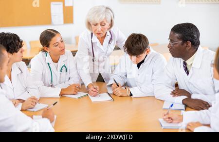 Ältere weibliche Professorin für Medizin, die Vortrag an die Gruppe von Praktikumsärzten hält Stockfoto