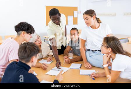 Freundliche afroamerikanische Englischlehrerin, die Sprachkurse für eine Gruppe von Erwachsenen gibt Stockfoto