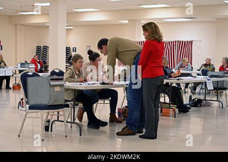 INDEPENDENCE , KANSAS - 8. NOVEMBER 2022 Kansas Generalanwalt Derek Schmidt der republikanische Gouverneurskandidat unterschreibt seine Stimmabgabe, bevor er sie an seinem Wahllokal in seiner Heimatstadt in die Wahlurne einsetzte.seine Frau Jennifer (rotes Hemd) steht neben ihm. Stockfoto
