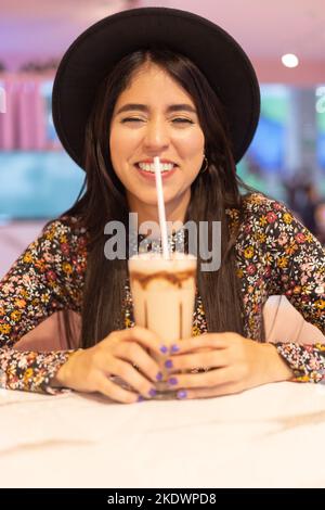 Glückliche junge Frau, die in einem Restaurant ein Glas mit Smoothie genießt, Gesichtsdetails, natürlichen Lebensstil Stockfoto