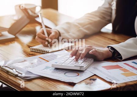 Geschäftsfrau, die einen Rechner verwendet, um eine Umsatz- und Gewinnrechnung auf dem Bericht zu berechnen Stockfoto
