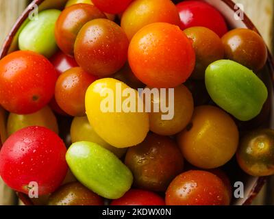 Helle Komposition aus bunten Tomaten. Nahaufnahme. Viele Objekte. Landwirtschaft, Supermarkt. Gesundes vegetarisches Essen. Vitamine, Antioxidantien, Diät-Lebensmittel. Stockfoto