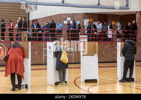 Hamtramck, Michigan, USA. 8.. November 2022. Die Wähler gaben bei den Zwischenwahlen 2022 an der Hamtramck High School ihre Stimme ab. Die Wähler füllen die Stimmzettel in den Wahlkabinen auf dem Hallenboden aus, während die Wähler in einem anderen Bezirk oben Schlange stehen. Kredit: Jim West/Alamy Live Nachrichten Stockfoto