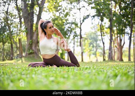Portrait einer wunderschönen jungen Frau, die im Freien Yoga praktiziert. Stockfoto
