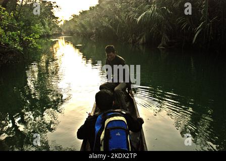 Nationalpark-Ranger entspannen sich, während sie auf einer Bootsfahrt durch den Cigenter River auf Handeuleum Island, einem Teil des Ujung Kulon Nationalparks in Pandeglang, Banten, Indonesien, verweilen. Stockfoto