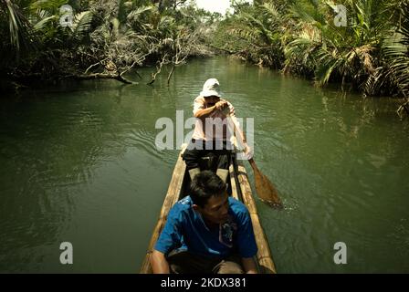 Nationalpark-Ranger, die mit dem Boot durch den Cigenter River auf Handeuleum Island fahren, einem Teil des Ujung Kulon National Park in Pandeglang, Banten, Indonesien. Stockfoto