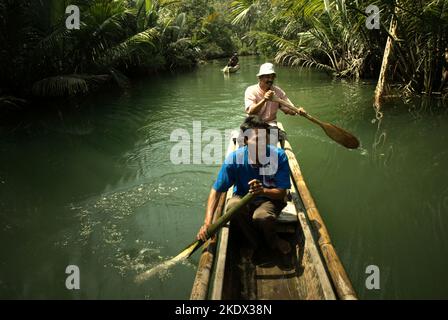 Nationalpark-Ranger, die mit dem Boot durch den Cigenter River auf Handeuleum Island fahren, einem Teil des Ujung Kulon National Park in Pandeglang, Banten, Indonesien. Stockfoto