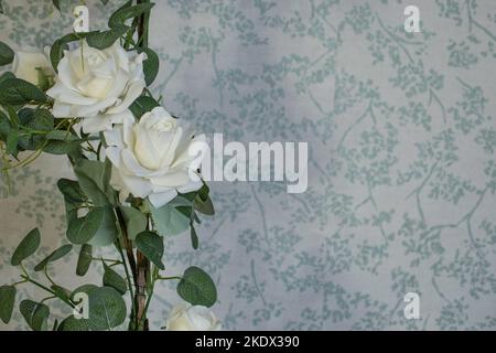 Künstliche Rosen verzweigt sich auf defokussierten floralen Muster grauen Tapeten, weichen Fokus Nahaufnahme Stockfoto