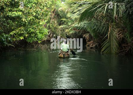 Nationalpark-Ranger, die mit dem Boot auf dem Cigenter River durch den Tieflandwald der Handeuleum Island fahren, einem Teil des Ujung Kulon Nationalparks in Pandeglang, Banten, Indonesien. Stockfoto