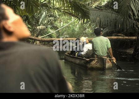 Nationalpark-Ranger und Journalisten reisen mit dem Boot auf dem Cigenter River durch den Tieflandwald der Handeuleum Island, einem Teil des Ujung Kulon Nationalparks in Pandeglang, Banten, Indonesien. Stockfoto