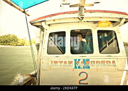 Ein Mann, der ein Boot steuert, das für einen Ausflug auf der Sunda-Straße im Ujung Kulon-Nationalpark in Pandeglang, Banten, Indonesien, gemietet wird. Stockfoto