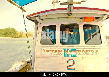 Ein Mann, der ein Boot steuert, das für einen Ausflug auf der Sunda-Straße im Ujung Kulon-Nationalpark in Pandeglang, Banten, Indonesien, gemietet wird. Stockfoto