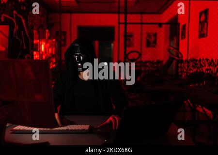 Porträt eines gesuchten, nicht erkennbaren Hacker-Mannes, der in schwarzer Maske und Sweatshirt mit Kapuze in Sicherheitssystemen eingriff Stockfoto