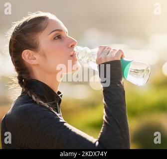 Eine attraktive junge Frau, die während ihres Trainings Wasser trinkt. Stockfoto