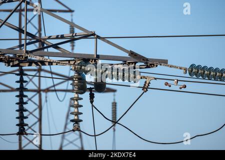 Isolatoren von Hochspannungsfreileitungen stehen tagsüber unter blauem Himmel Stockfoto