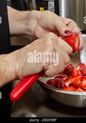 Der Koch schneidet Erdbeeren zum Dessert in der eigenen Küche Stockfoto