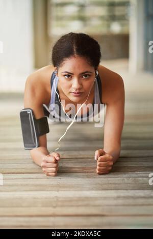 Am Ende werden die Ergebnisse den Schmerz wert sein. Porträt einer sportlichen jungen Frau, die zu Hause auf ihrer Terrasse Plankenübungen macht. Stockfoto