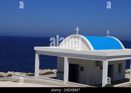 26. Mai 2022, Larnaca, Zypern: Die Agioi Anargyroi Kirche am Kap Greco liegt am Rande einer vertikalen Felsklippe über dem Meer. Es ist den Heiligen Kosmas und Damianos gewidmet. Unterhalb der Kapelle befindet sich eine Höhle mit dem heiligen Wasser der Heiligen. Die Republik Zypern steht an einem historischen und kulturellen Scheideweg zwischen Europa und Asien. Seine Hauptstädte - die Hauptstadt von Nikosia, Limassol, Famagusta und Paphos haben die Einflüsse von Generationen von Eroberern, Pilgern und Reisenden absorbiert und haben eine Atmosphäre, die sowohl kosmopolitisch als auch provinziell ist. (Bild: © Ruaridh Stewart/ZUMA Press Wire Stockfoto