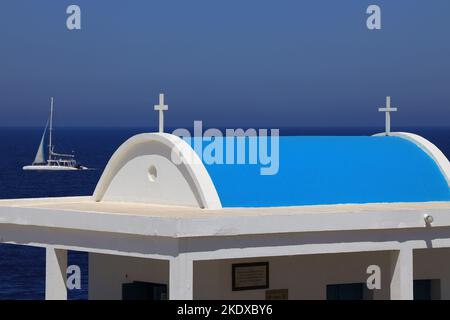 26. Mai 2022, Larnaca, Zypern: Das Segelboot fährt hinter der Agioi Anargyroi-Kirche am Kap Greco vorbei und liegt am Rand einer vertikalen Felsklippe über dem Meer. Es ist den Heiligen Kosmas und Damianos gewidmet. Unterhalb der Kapelle befindet sich eine Höhle mit dem heiligen Wasser der Heiligen. Die Republik Zypern steht an einem historischen und kulturellen Scheideweg zwischen Europa und Asien. Seine Hauptstädte - die Hauptstadt von Nikosia, Limassol, Famagusta und Paphos haben die Einflüsse von Generationen von Eroberern, Pilgern und Reisenden absorbiert und haben eine Atmosphäre, die sowohl kosmopolitisch als auch provinziell ist. (Bild: © Ruaridh Stockfoto