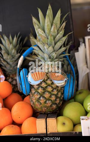 Larnaca, Zypern. 24.. Mai 2022. Ananas an einem Fruchtsaft und in Kopfhörern und Schattierungen. Die Republik Zypern steht an einem historischen und kulturellen Scheideweg zwischen Europa und Asien. Seine Hauptstädte - die Hauptstadt von Nikosia, Limassol, Famagusta und Paphos haben die Einflüsse von Generationen von Eroberern, Pilgern und Reisenden absorbiert und haben eine Atmosphäre, die sowohl kosmopolitisch als auch provinziell ist. Heute ist Zypern ein beliebtes Touristenziel für Besucher aus Europa, das von Hochzeitsreisenden bevorzugt wird (Foto: © Ruaridh Stewart/ZUMA Press Wire) Stockfoto