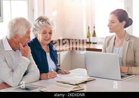 Könnten Sie die Renditen unserer Investitionen noch einmal durchgehen? Ein hochrangiges Paar erhält Rat von seinem Finanzberater. Stockfoto