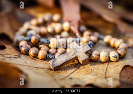 Hölzerne Rosenkranz-Perlen liegen auf den Herbstblättern. Stockfoto