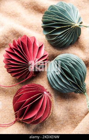 Handgemachte Öko Papierkugel, Nahaufnahme. Weihnachtsdekoration auf braunem Strickhintergrund. Stockfoto