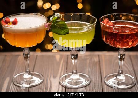 Drei verschiedene Cocktails in warmen Farben auf hellem Hintergrund. Cocktail- oder Barmenü Stockfoto