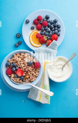 Eine Schüssel mit trockenem Müsli, serviert mit frischem Beerenobst und Joghurt. Haferflockenplatte. Gesunde Ernährung, Ernährung. Draufsicht. Stockfoto