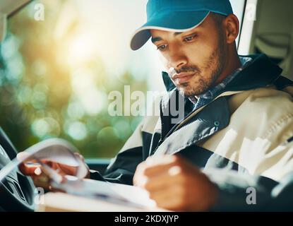 Er plant, wo er sein muss: Ein Kurier, der in seinem Lieferwagen Lieferungen macht. Stockfoto