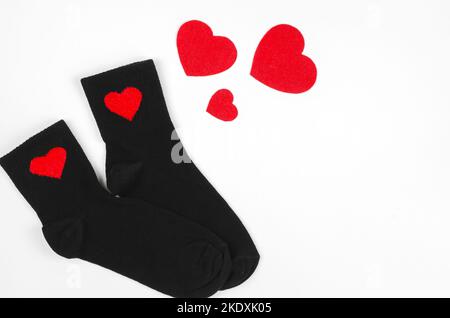 Schwarze Socken mit roten Herzen isoliert auf weißem Hintergrund. Das Konzept der Fürsorge für die Angehörigen. Stockfoto