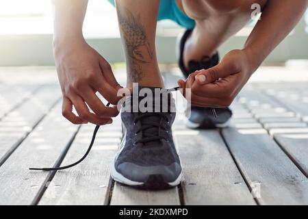 Schnüren Sie sich, bevor Sie sich Formen. Eine sportliche junge Frau schnürt ihre Schnürsenkel. Stockfoto