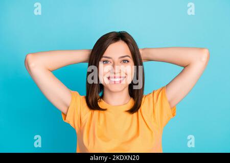 Foto von zufriedenen wunderschönen schönen Mädchen gekleidet gelb T-Shirt halten Hände hinter dem Kopf entspannen isoliert auf türkisfarbenem Hintergrund Stockfoto